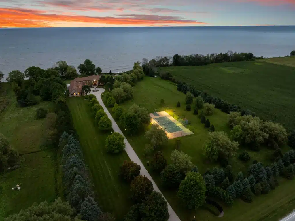 Drone view of Mansion on the Lake, a luxury Lake Michigan vacation rental with expansive landscape, tennis court, pool, and lakefront setting near Chicago.