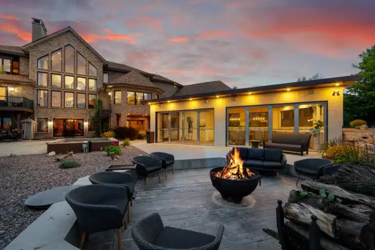 Back view of Mansion on the Lake facing Lake Michigan, with hot tub, outdoor fireplace, and summer house with full kitchen and covered area for gatherings