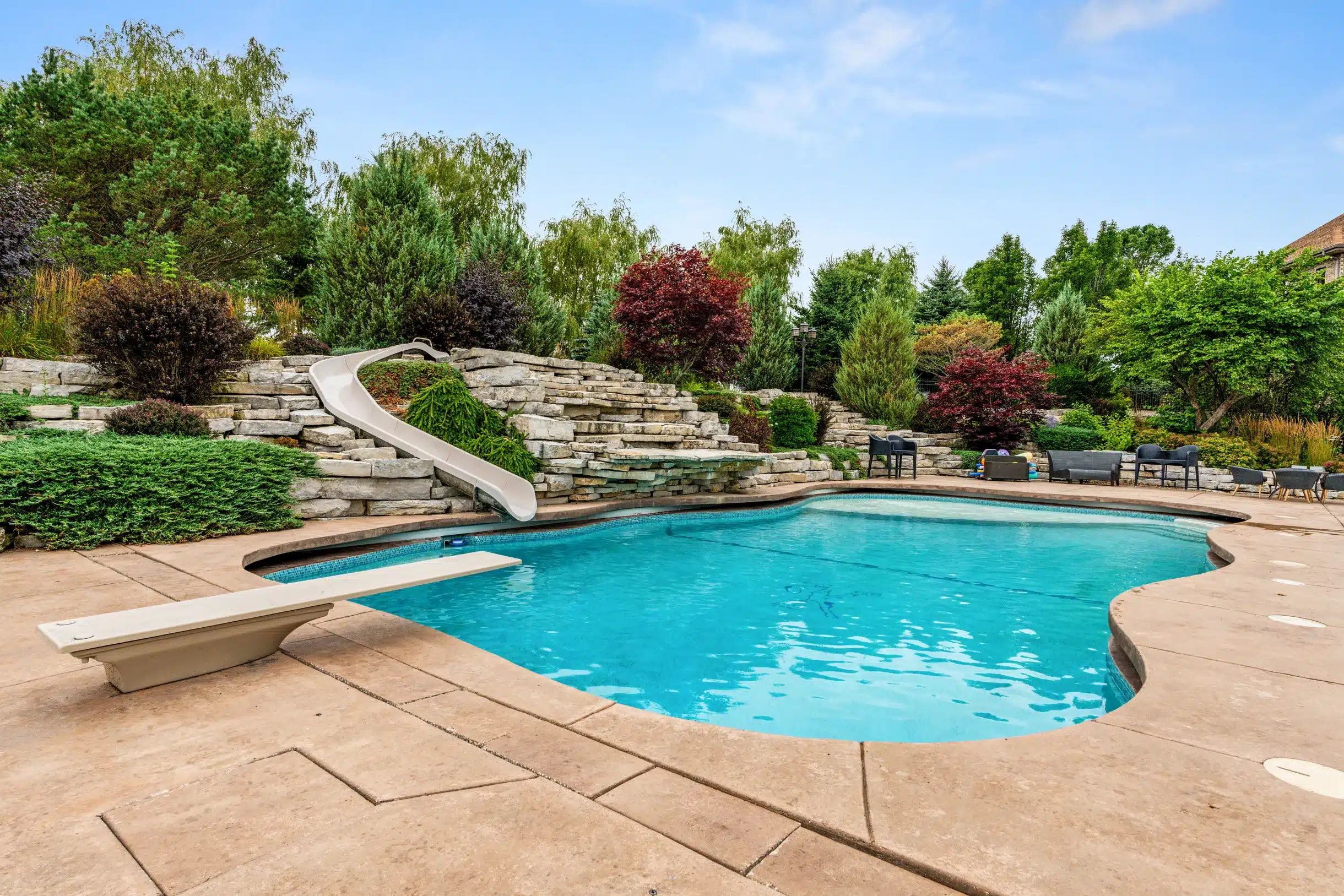 Outdoor pool at Mansion on the Lake with slide, diving board, and comfortable seating area.