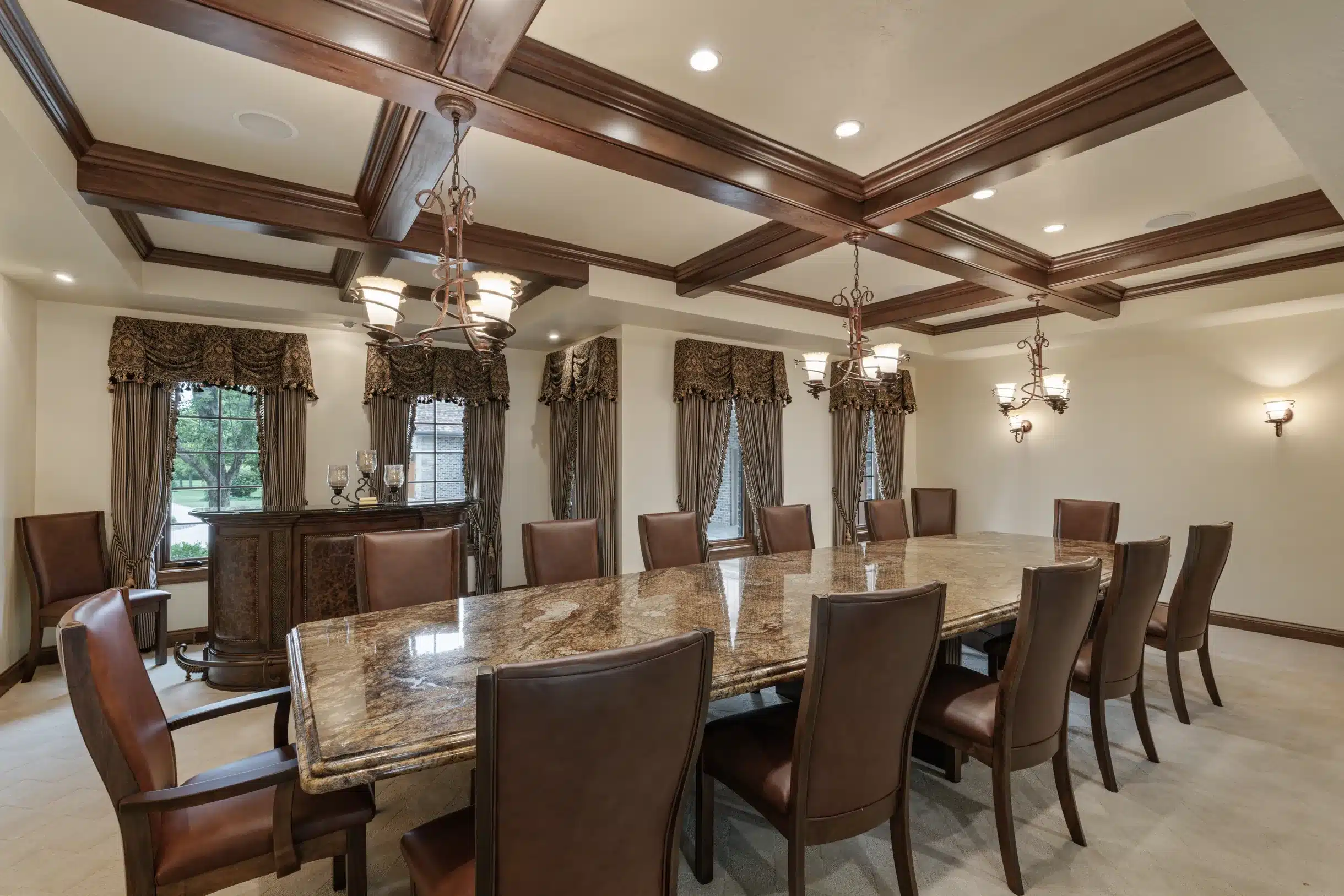 Full view of the Mansion on the Lake dining room with a grand table, plush chairs, bar area, and large windows overlooking the landscape.